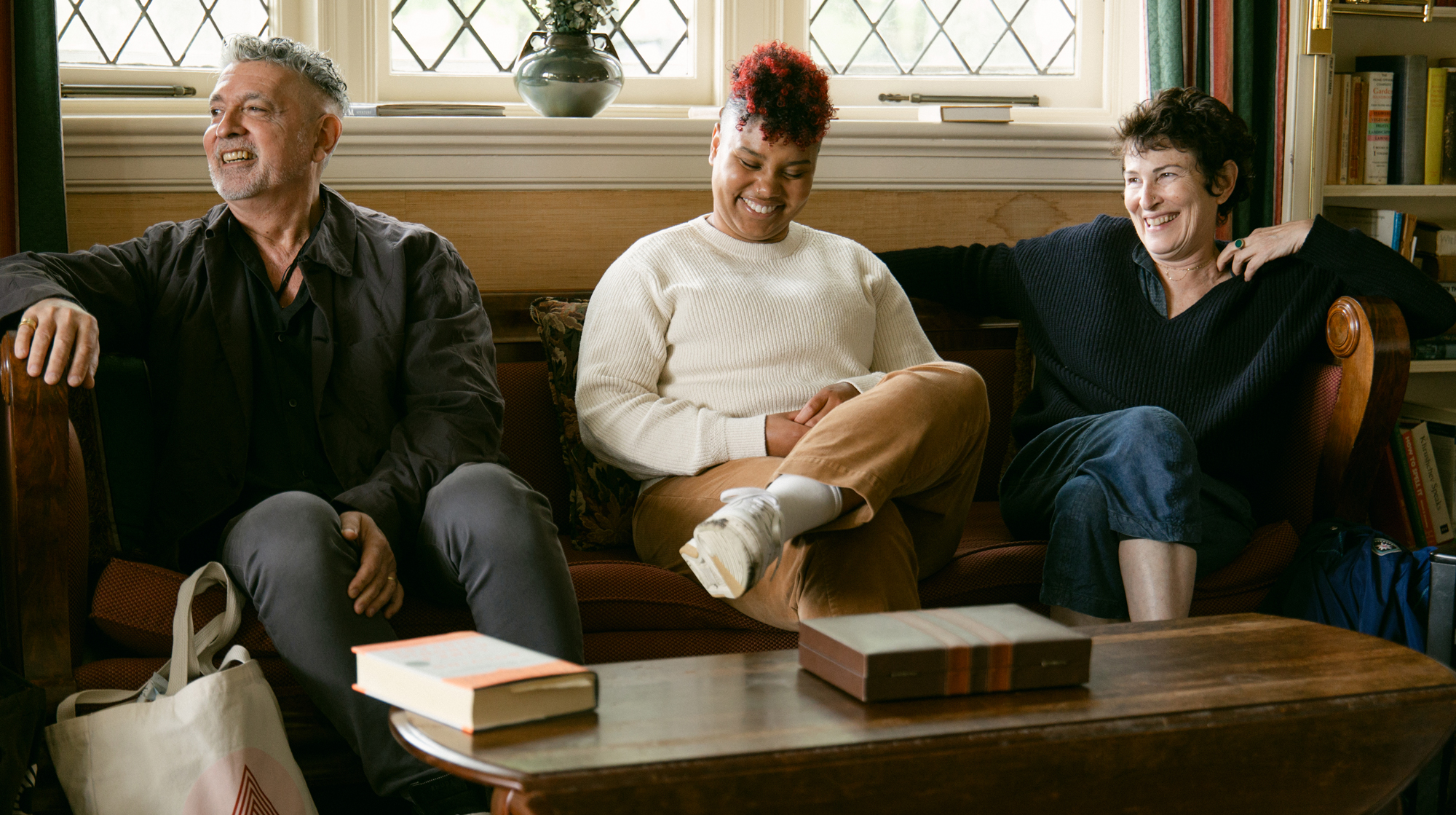 Three people laughing in a sunlit room
