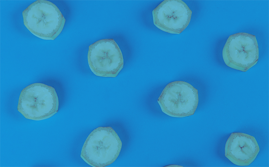 The image is filtered in a dual-tone style, with the banana slices appearing in a pale teal color. Each cross-section clearly illustrates a Fibonacci number by showing the fruit's natural 3-segment internal structure, with tiny dark seeds clustered in the center forming a three-pointed star shape.