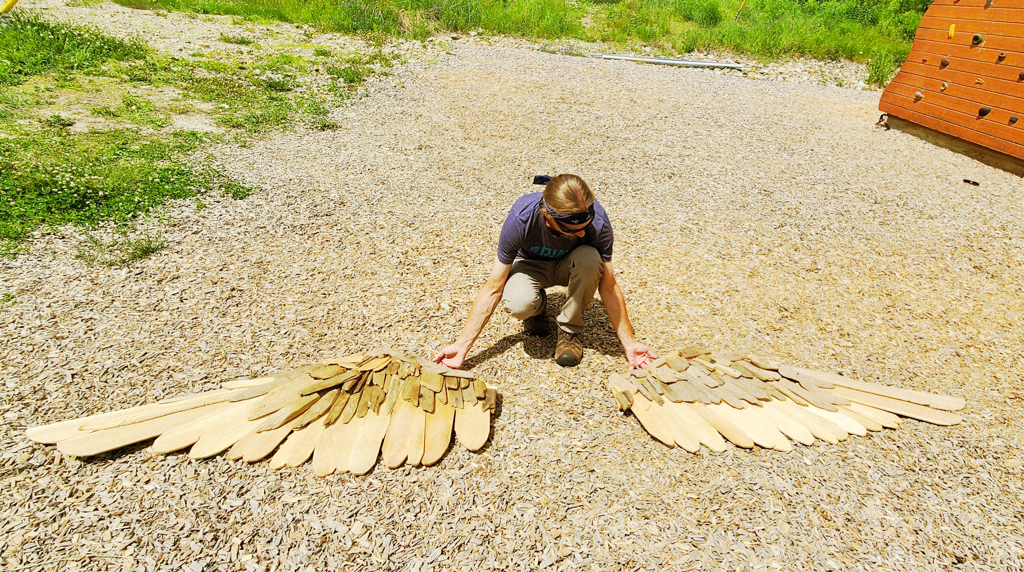 Person kneeling in front of wooden wings.